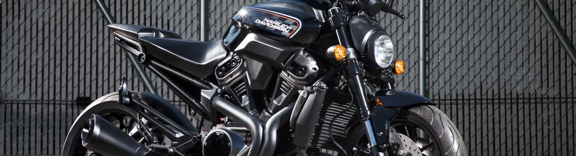 A black, Harley-Davidson motorcycle is parked within the perimeter of an outdoor storage facility.