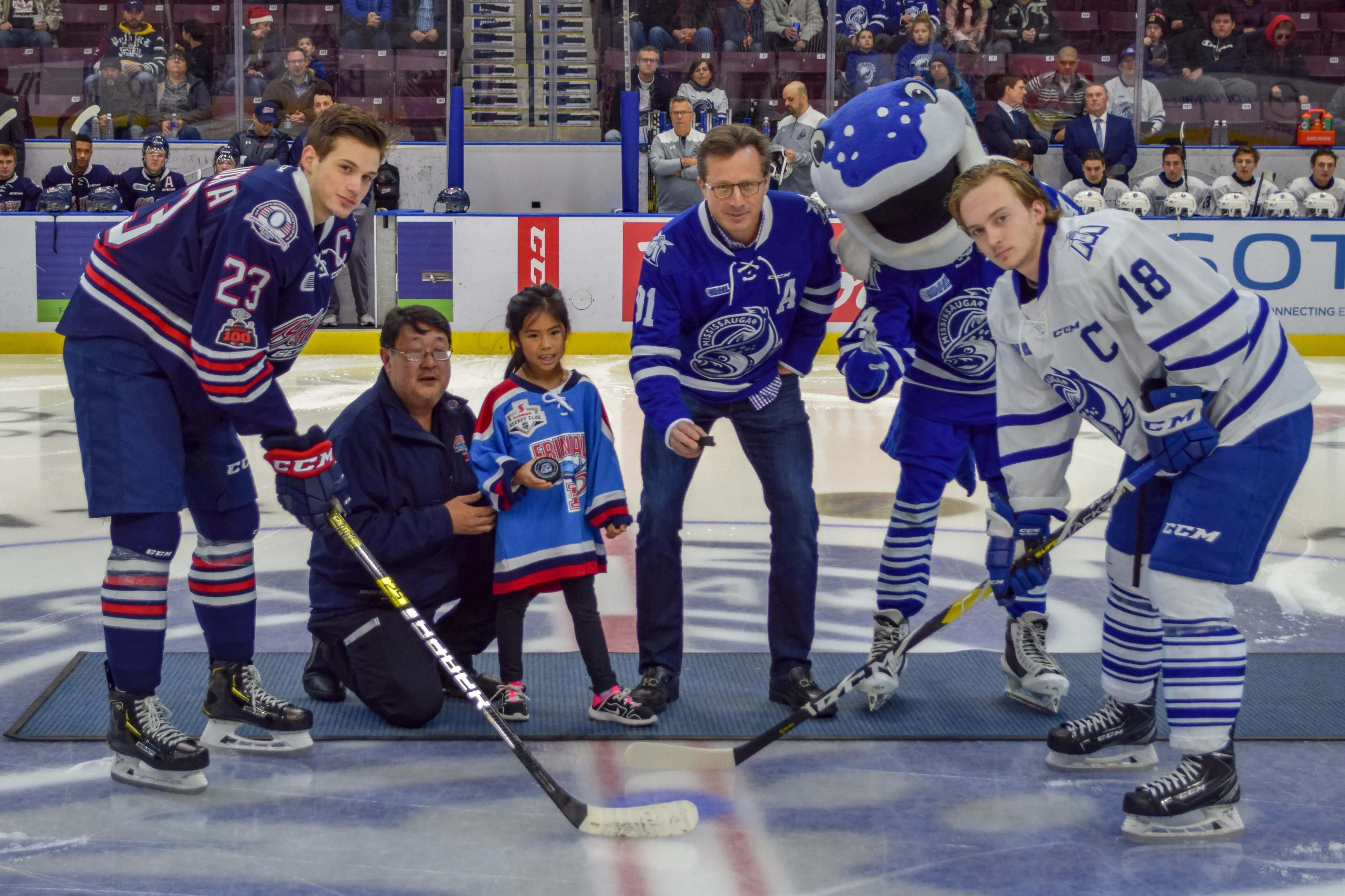 Le président-directeur général de SmartStop pose avec les joueurs et la mascotte de Mississauga lors d'une cérémonie de mise en jeu.