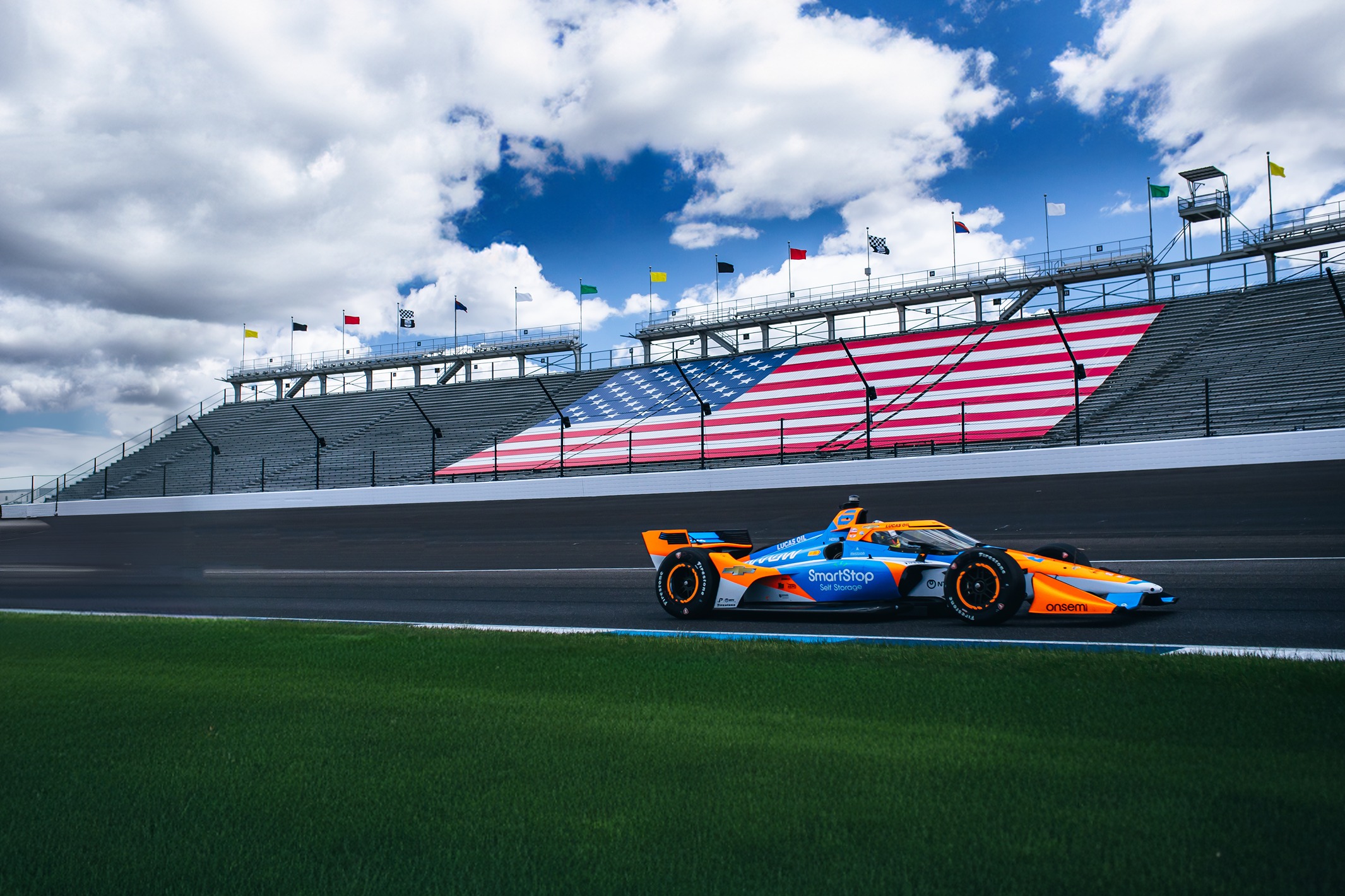 Image of SmartStop IndyCar on racetrak in front of huge American flag in stadium | SmartStop