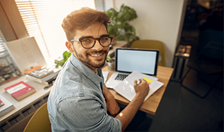 Image of smiling student at small desk with a computer