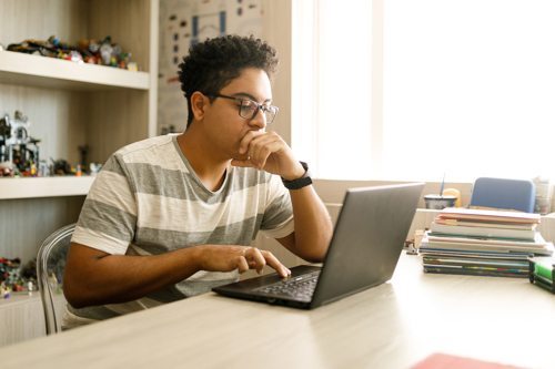 teen studying at his laptop in bedroom