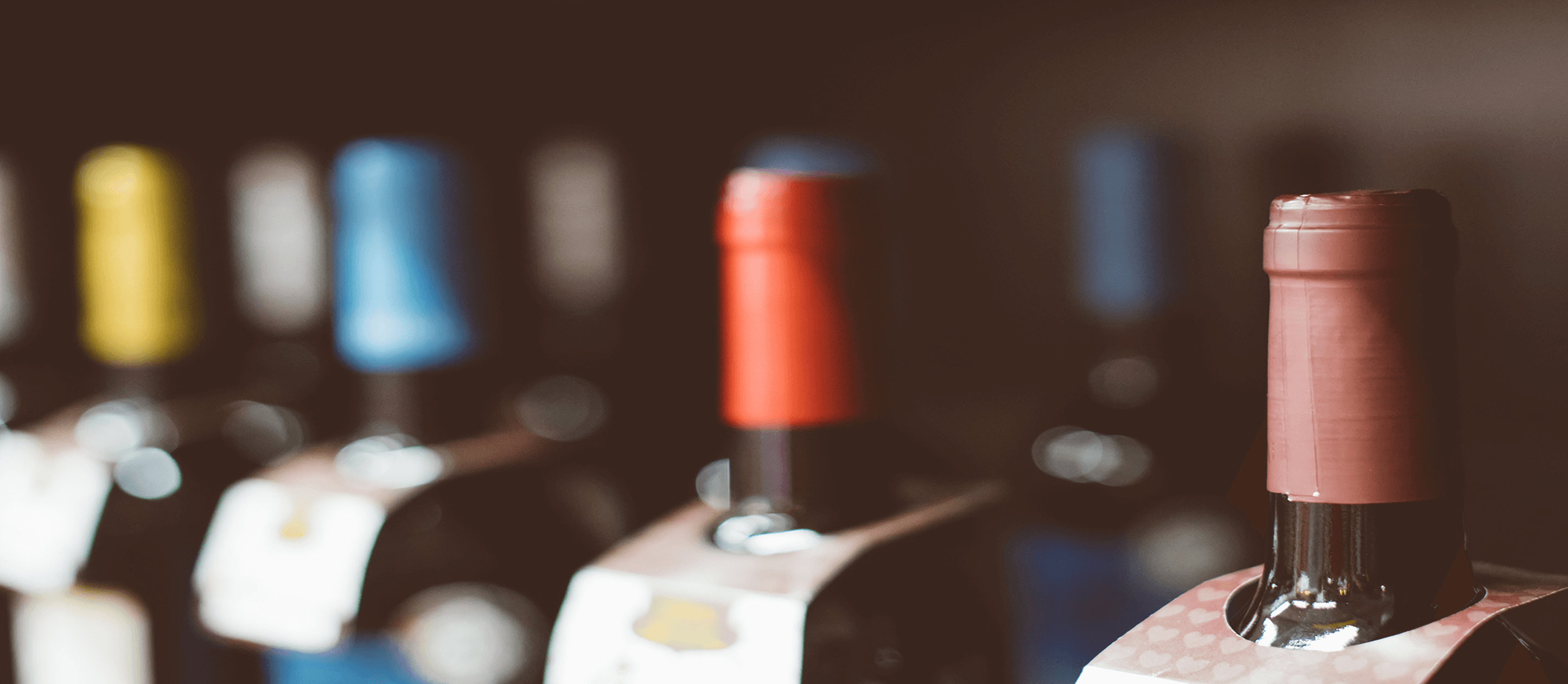 bottles of wine with a variety of colored tops