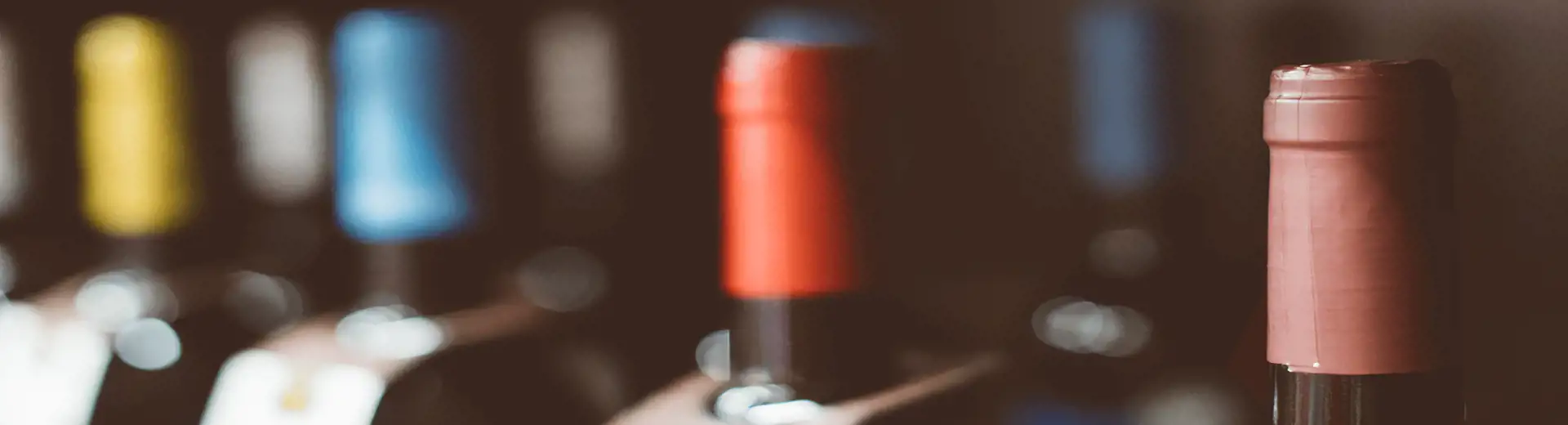 bottles of wine with a variety of colored tops