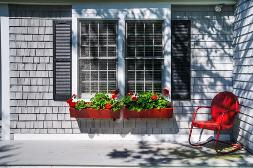 red flowers in red-painted window boxes