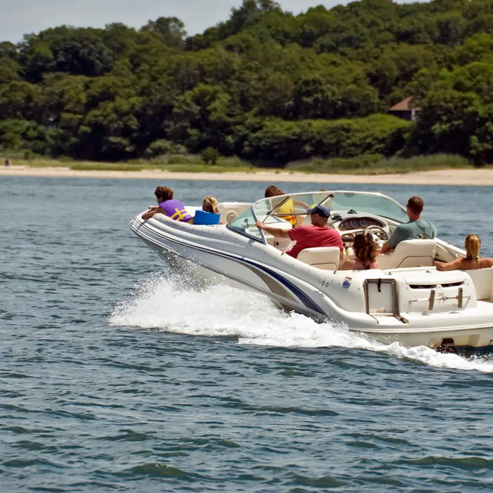 Family taking a ride in their boat on a lake with the shorline and trees in the background
