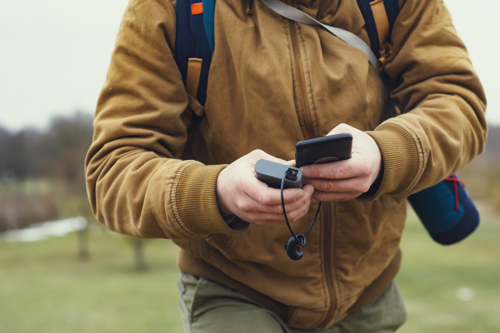 man traveling using a portable power bank to charge his phone