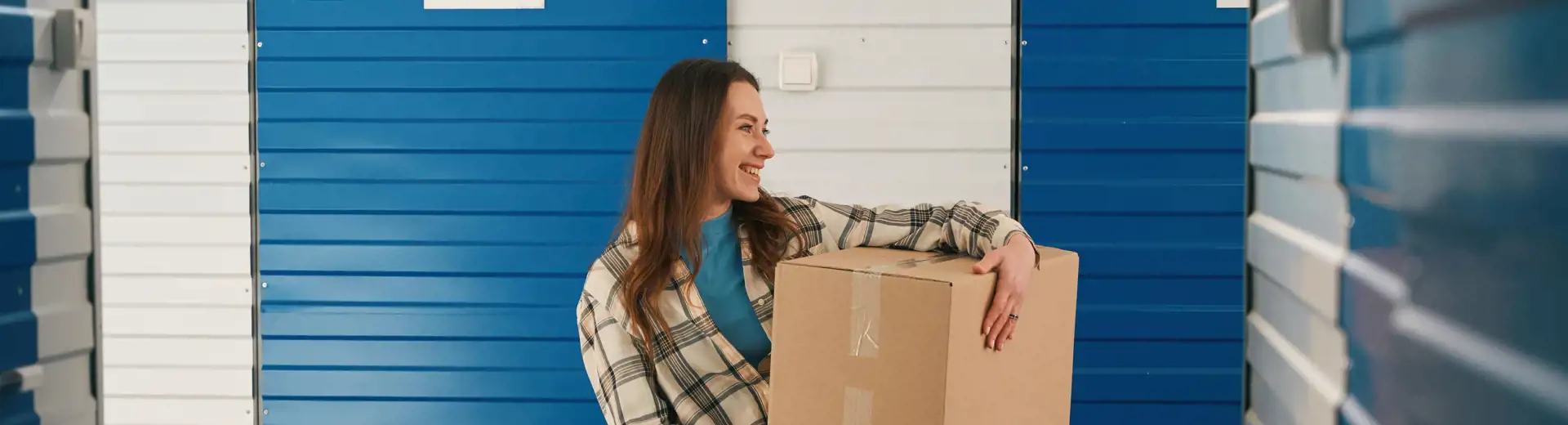 woman holding cardboard box outside of storage unit