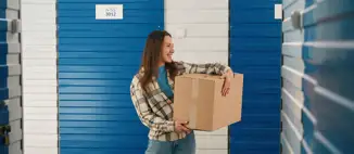 woman holding cardboard box outside of storage unit