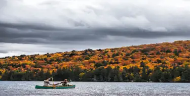 image of canoe on lake surrounded by colorful trees