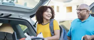 man and daughter unloading trunk of car during college move in day