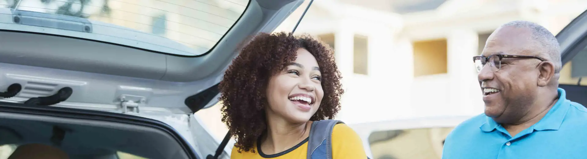 man and daughter unloading trunk of car during college move in day