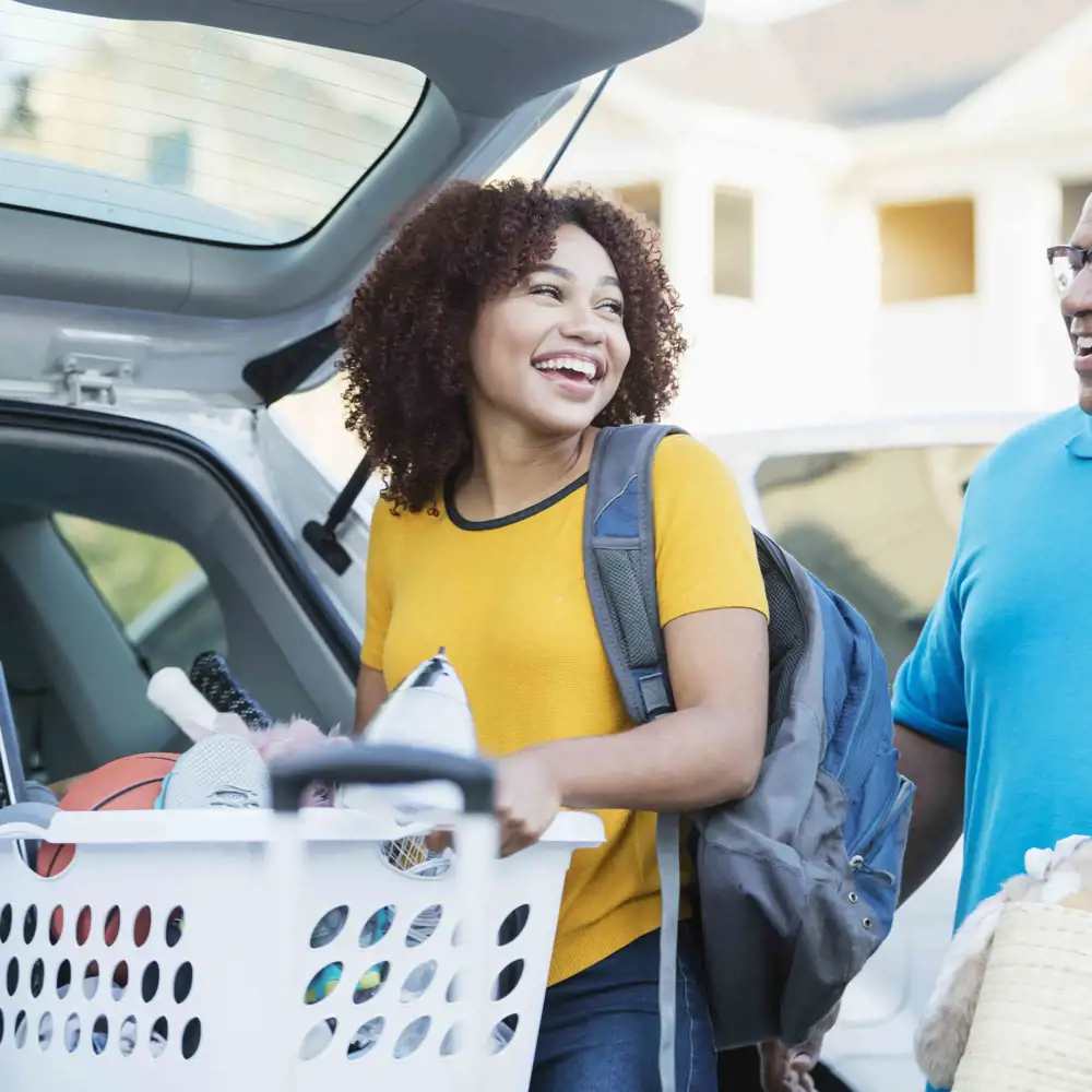 man and daughter unloading trunk of car during college move in day