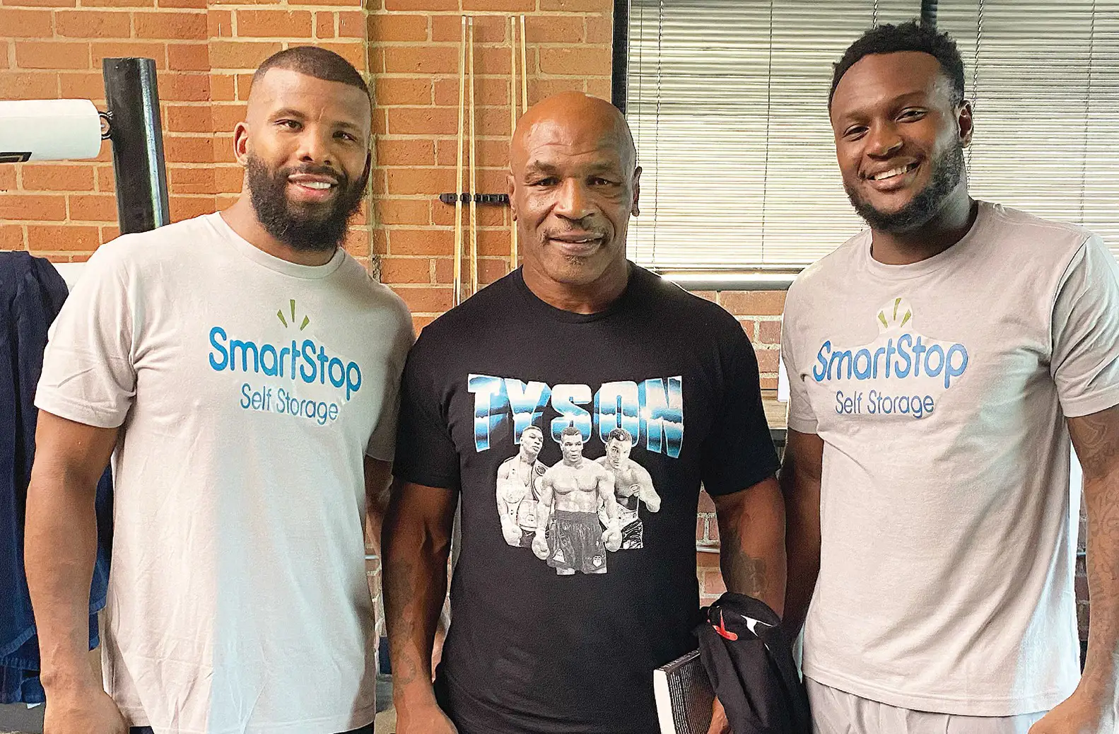 Mike Tyson pose avec deux boxeurs qui s'apprêtent à combattre lors d'un événement