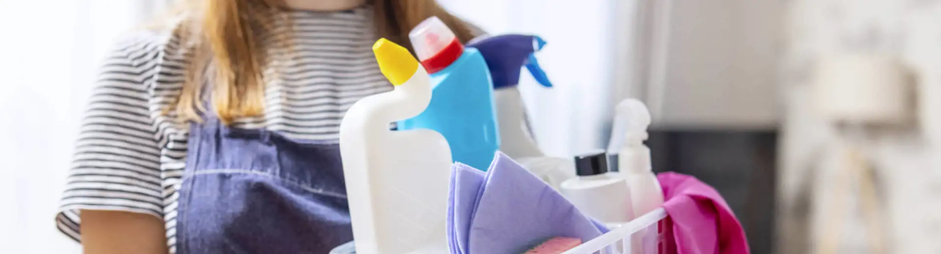 woman holding cleaning caddy and apron