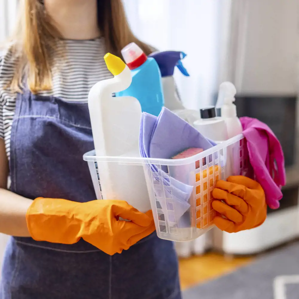 woman holding cleaning caddy and apron