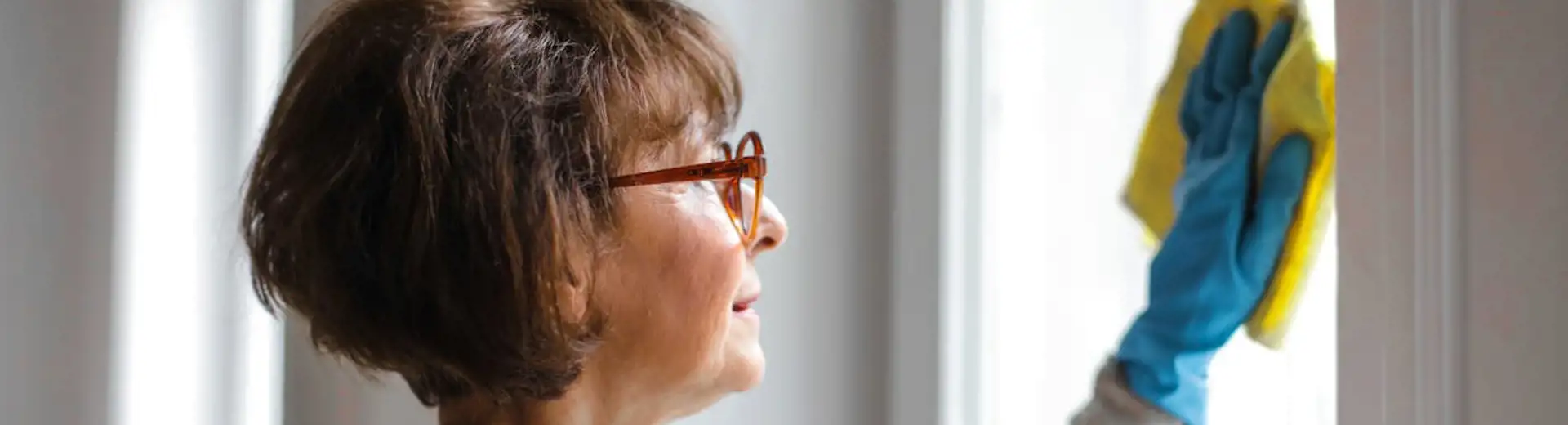 woman with glasses wiping window with microfiber cloth