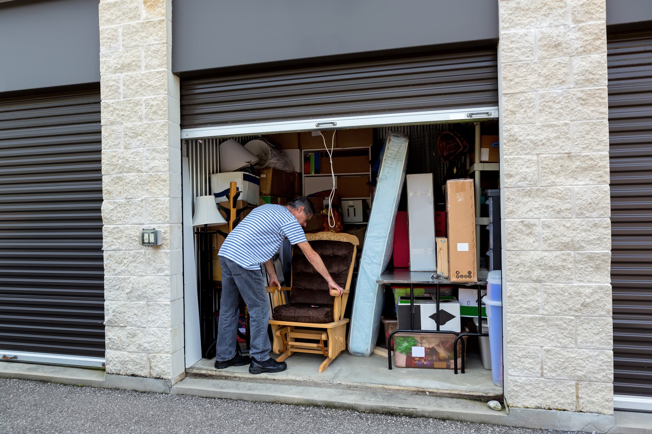 man storing a rocking chair in crowded self-storage unit