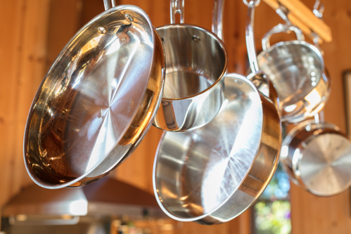 stainless steel pots and pans hanging from a ceiling rack in a kitchen
