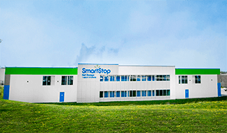Image de l'extérieur d'un bâtiment SmartStop avec de l'herbe verte et un ciel bleu