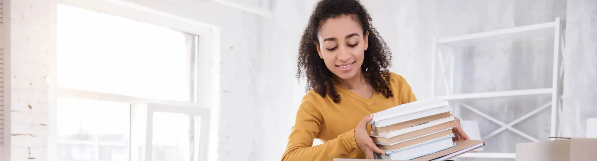 college student placing books into a cardboard moving box