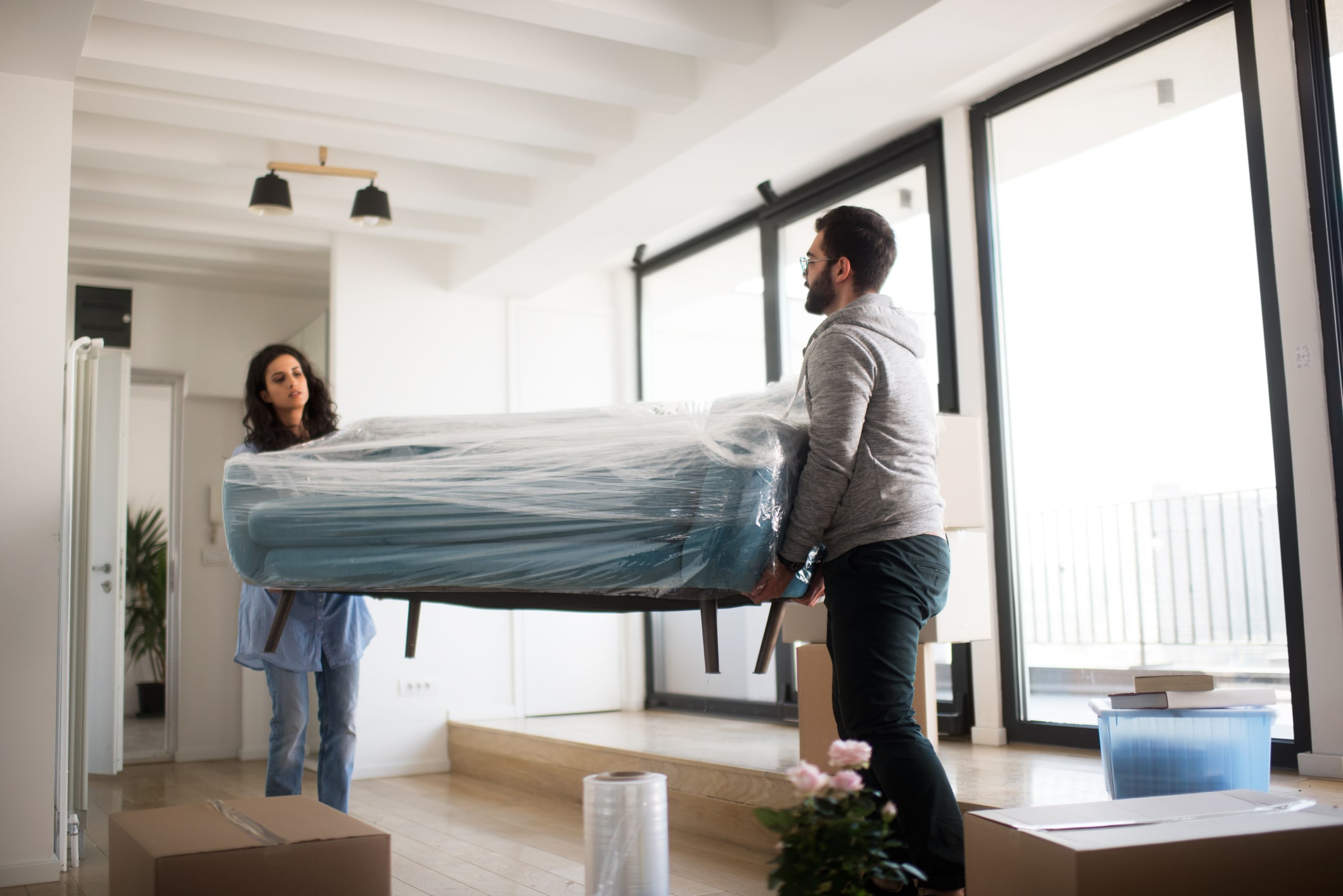 couple moving wrapped sofa out of home