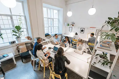 Image of an office workspace with happy workers at computers and desks