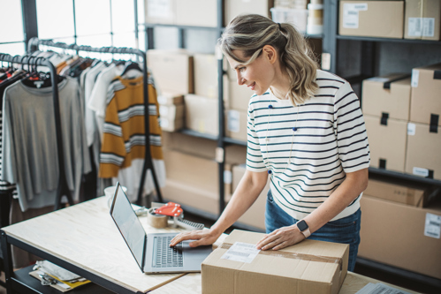 female business owner surrounded by inventory printing label to attach to shipping box
