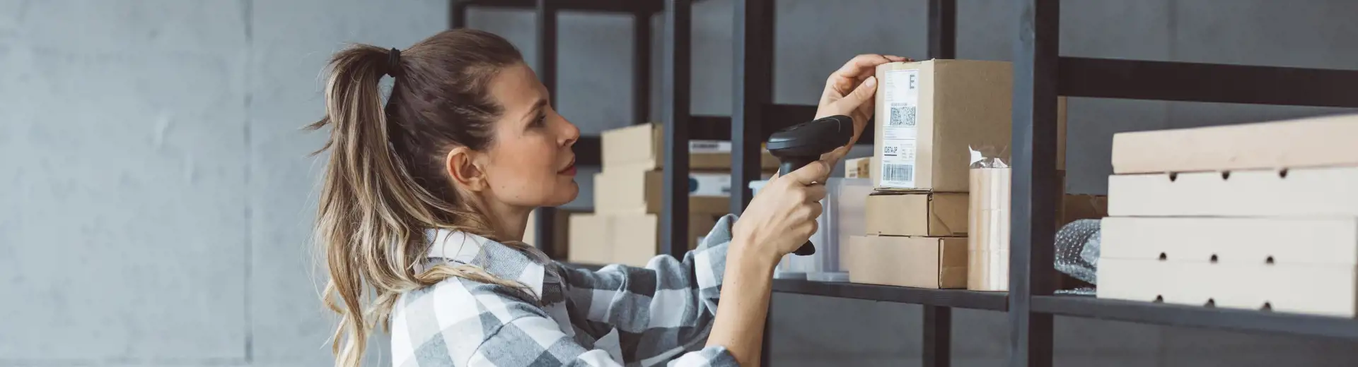 woman scanning barcode of box on shelving unit in storage