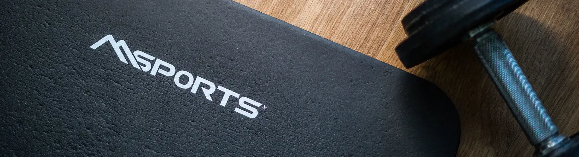black yoga mat and dumbbell on a wooden floor