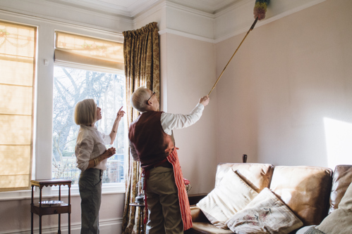couple working together to dust crown molding