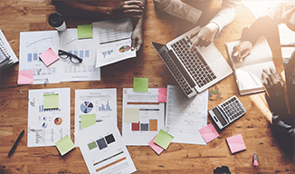 Overhead image of a table with papers spread out and a computer being used