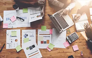 Vue sur une table avec des papiers étalés et un ordinateur portable en cours d'utilisation