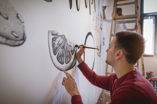 man painting mural on his living room wall