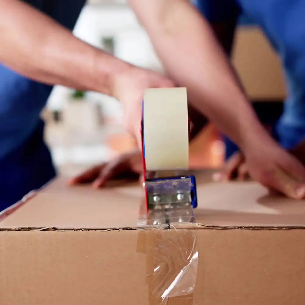 two movers taping cardboard box shut
