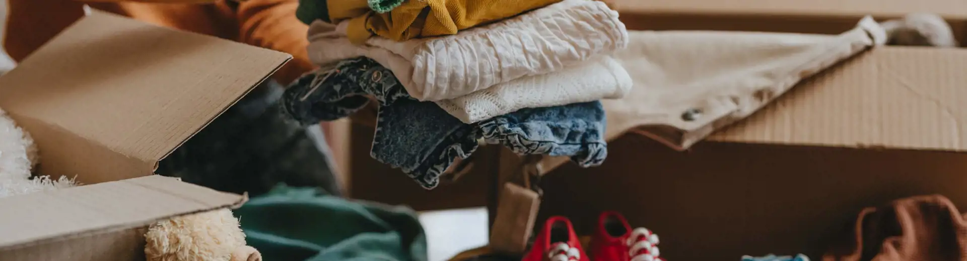 woman placing folded clothes into box for summer storage