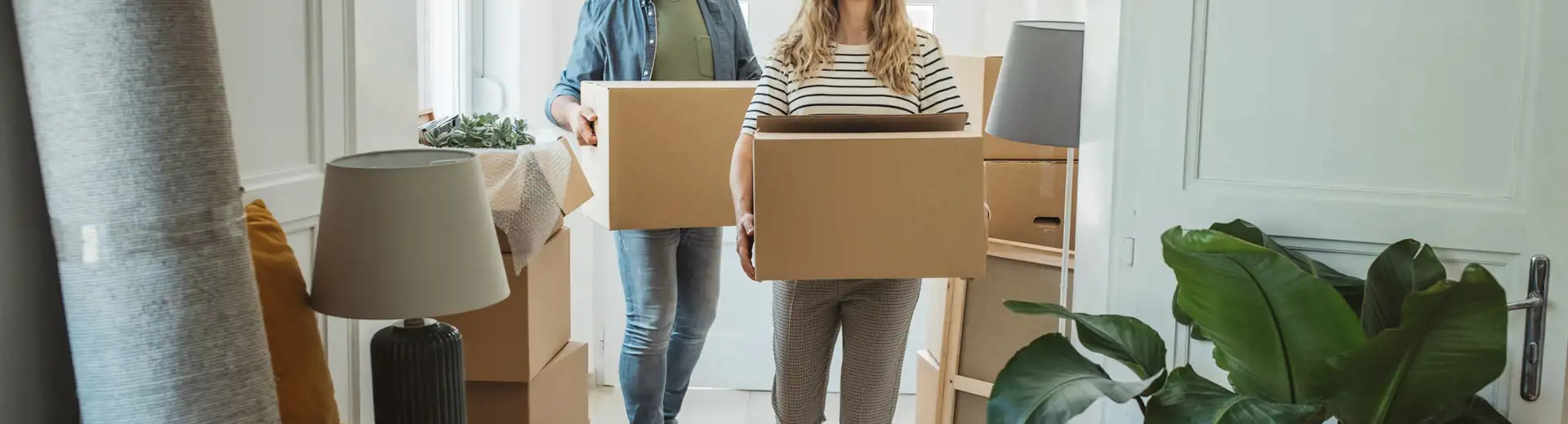 man and women carrying moving boxes through home entryway