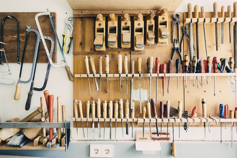 A picture of well-organized tools hanging on shelves and hooks a wall