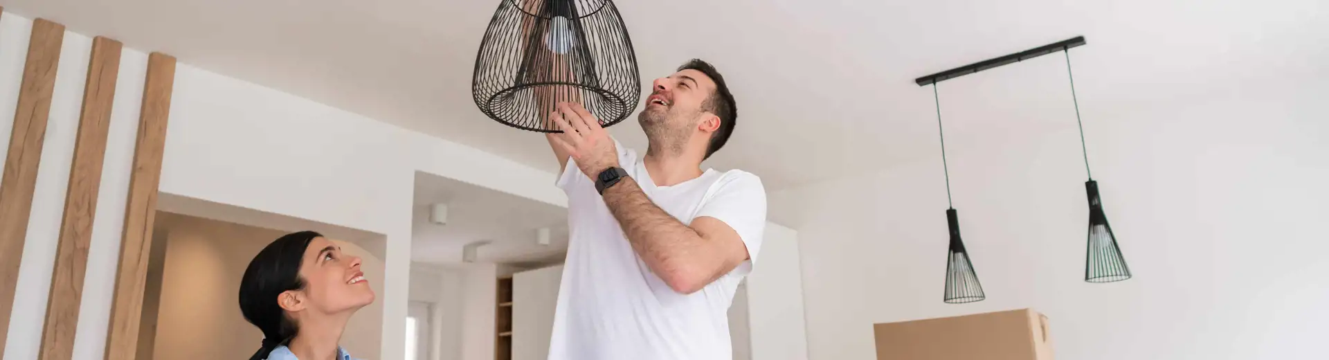 couple installing new design pendant light fixture in living room