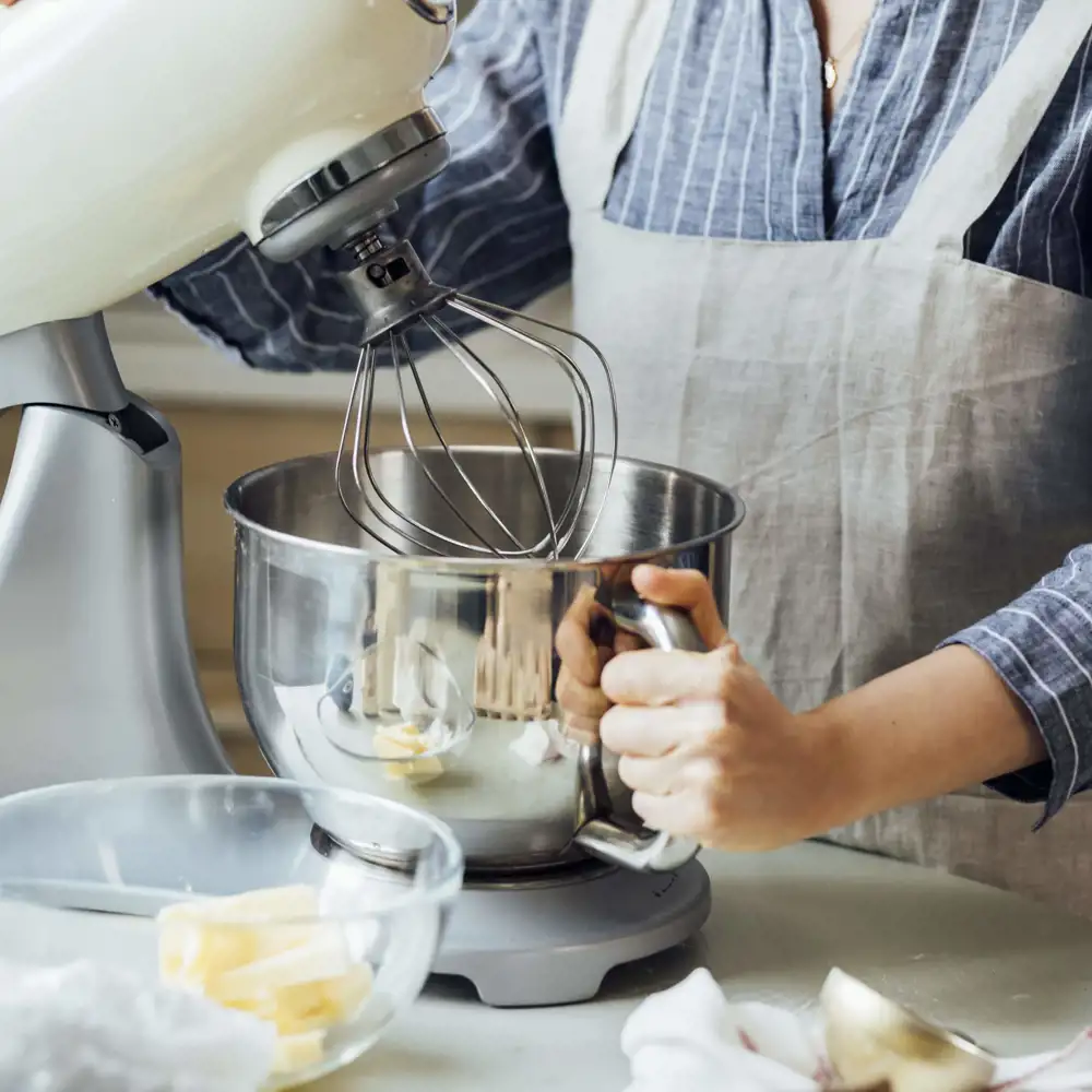 man wearing apron using kitchen stand mixer