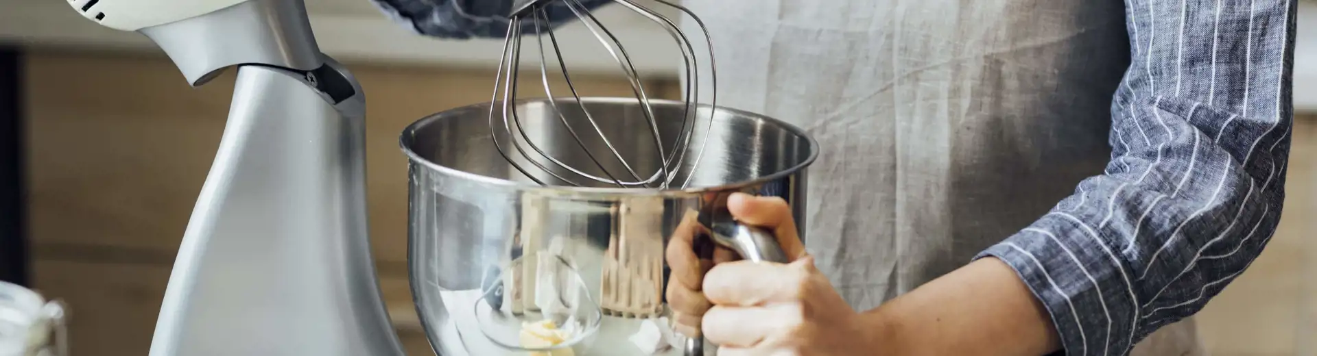 man wearing apron using kitchen stand mixer