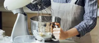 man wearing apron using kitchen stand mixer