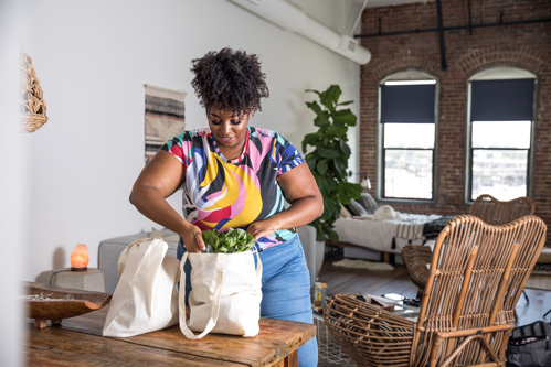 woman at home unpacking vegetables from reusable grocery bag