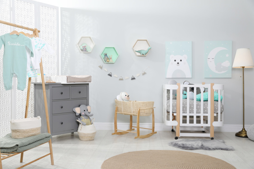 chambre de bébé chaleureuse avec berceau, commode, portant de vêtements et décoration murale pastel