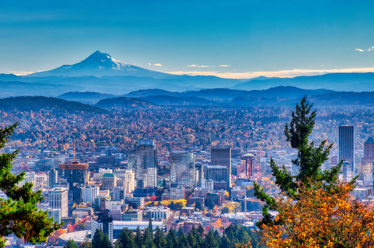 shot of portland skyscrapers set against a backdrop of trees, hills, and mountains
