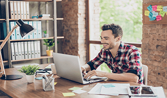 Image d'un homme heureux tapant sur un ordinateur portable ouvert sur un bureau