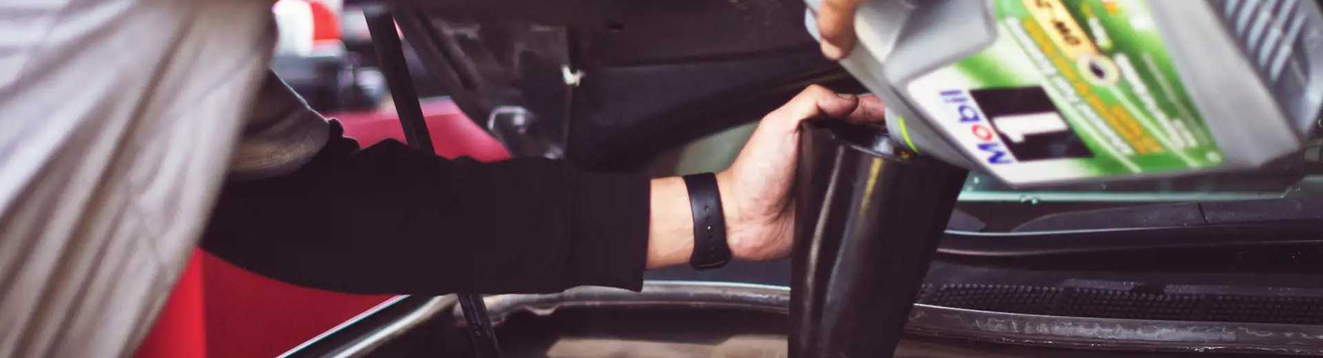 Mechanic putting oil in car engine