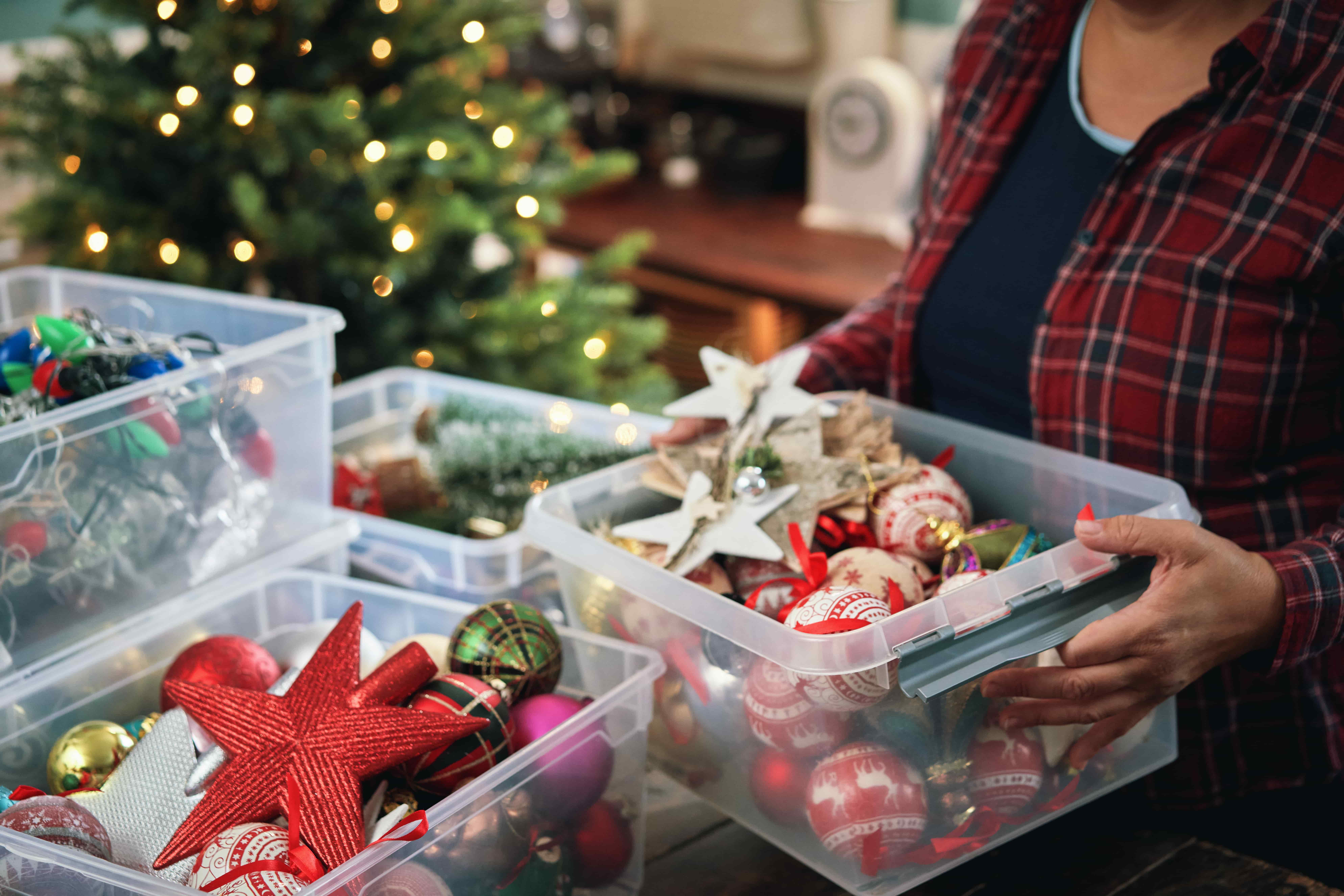 woman organizing holiday ornaments in clear plastic bins