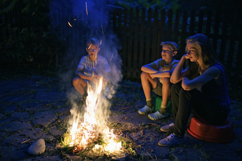 kids sitting around a backyard bonfire