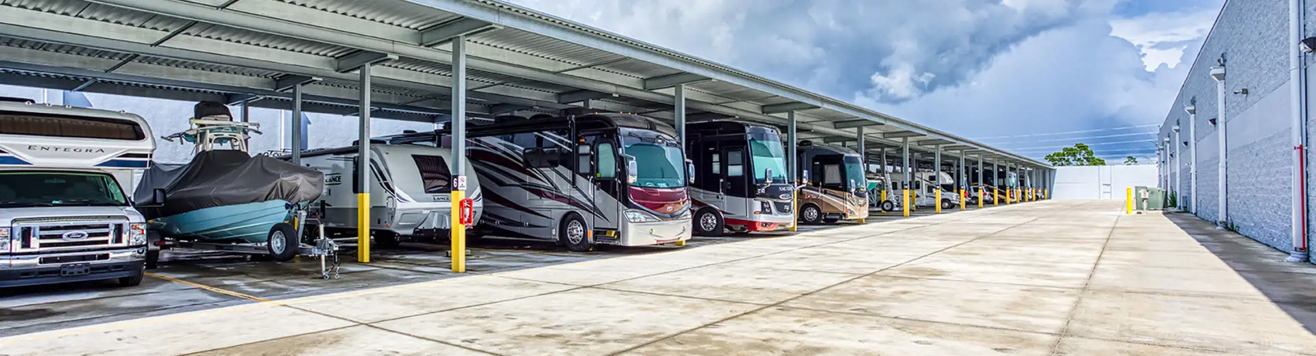 A photo of 7 RVs parked alongside each other with a forest and mountain scenery in the background.