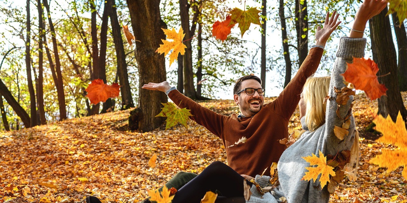 Image of couple throwing fall leaves into the air in celebration of seasonal savings on storage | SmartStop Self Storage in celebration of Halloween | SmartStop